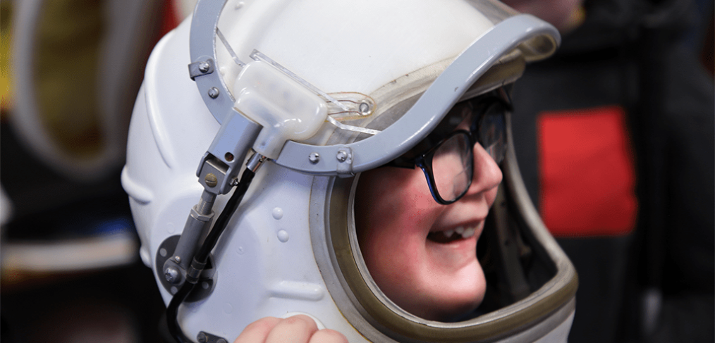 A student from the North Dakota School for the Blind tests out one of UND’s space helmets. Photo by Walter Criswell/UND Today.