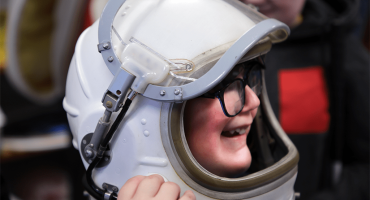 A student from the North Dakota School for the Blind tests out one of UND’s space helmets. Photo by Walter Criswell/UND Today.