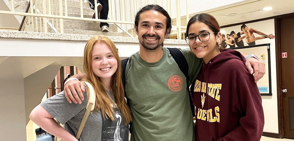 The technological leadership majors. From left: Lindsey Tober, Matthew Marquez and Elizabeth Garayzar. Three students smiling, standing arms in arm in campus building.