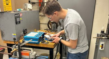 Ashton Ventura, a metallurgical engineering student, cleans the surface of a titanium sample before spot-welding a thermocouple
