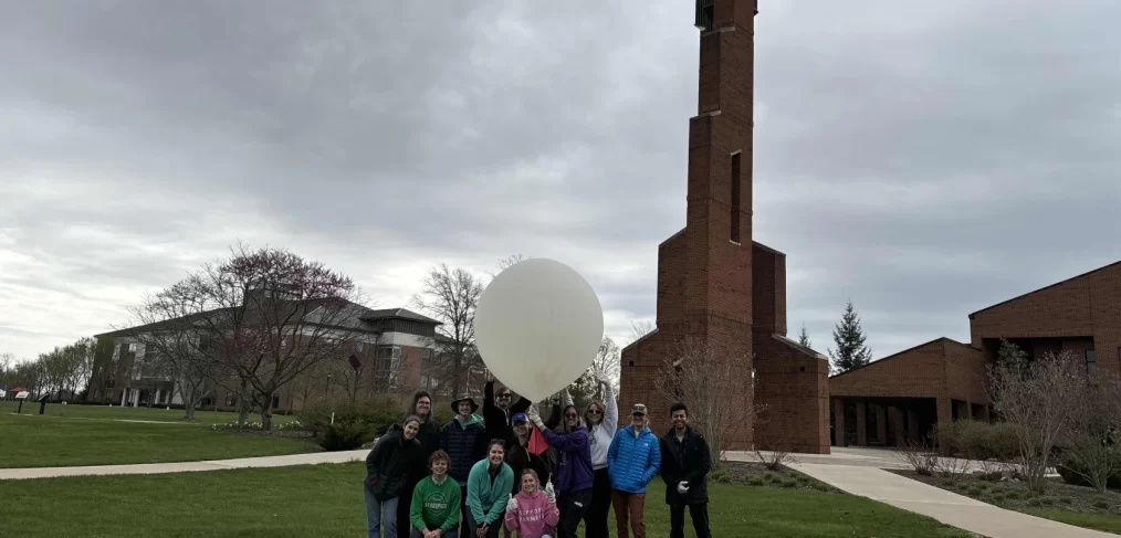 UND ballooning team poses outdoors on a university campus with one of their weather balloons