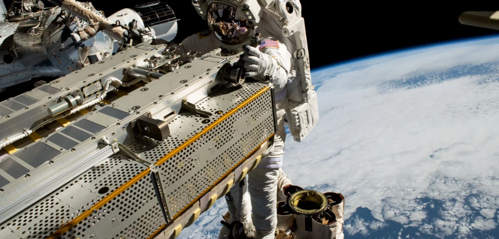 NASA astronaut in space suit on EVA outside ISS with Earth in the background