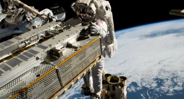 NASA astronaut in space suit on EVA outside ISS with Earth in the background