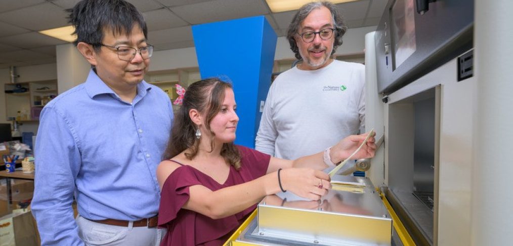 Michelle Yatvitskiy, a recent graduate of the fashion and apparel studies master’s program (center), holds a strip of a new fabric for the outer layer of space suits that was the result of a collaboration between the fashion and chemical engineering departments and a company founded by Blue Hen alumni. Yatvitskiy is accompanied by Huantian Cao, chair of the Department of Fashion and Apparel Studies (left), and chemical engineering professor Norm Wagner (right).