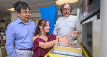 Michelle Yatvitskiy, a recent graduate of the fashion and apparel studies master’s program (center), holds a strip of a new fabric for the outer layer of space suits that was the result of a collaboration between the fashion and chemical engineering departments and a company founded by Blue Hen alumni. Yatvitskiy is accompanied by Huantian Cao, chair of the Department of Fashion and Apparel Studies (left), and chemical engineering professor Norm Wagner (right).