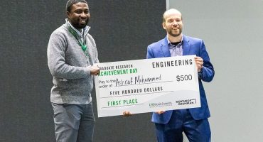 Ashraf Mohammed holds his first place check for $500 standing alongside Jason Hicks, systems engineering manager at Northrop Grumman. Photo by Walter Criswell/UND Today.