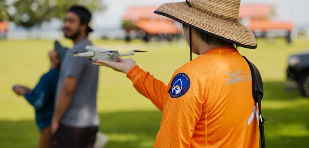 Student researcher holding drone in the field