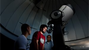 Student looking through telescope at Seton Hall University Astronomical Observatory