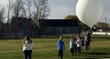 students standing outside with weather balloon