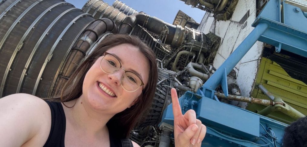 Hannah Jones pointing to rocket engines at NASA Stennis