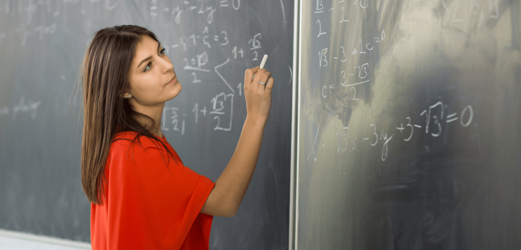 Student writing calculus equations on a blackboard with chalk