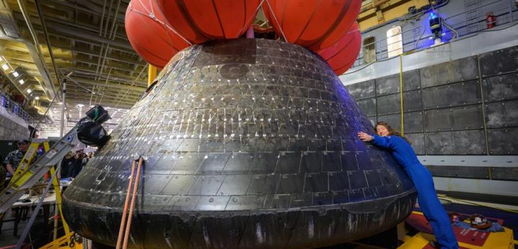 NASA astronaut Christina Koch, Artemis II mission specialist, hugs the Orion spacecraft aboard the USS John P. Murtha, following the spacecraft’s April 11 splashdown in the Pacific Ocean off the California coast. Photo Courtesy of NASA/Bill Ingalls.