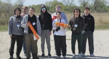 The UW-River Falls Falcon Rocketeers pose for a photo with their winning rocket at the 2026 NASA Wisconsin Space Grant Consortium Collegiate Rocket Launch Competition, held April 24-25 at Richard Bong State Recreational Area in Kansasville. Pictured L-R: Raidyn Bilotta, Sam Sackett, Jonathan Tabora, Peter Bendel, Evan Sander (back), Brook Mclaird (front), Mauricio Cuevas, Ian Vanveen.